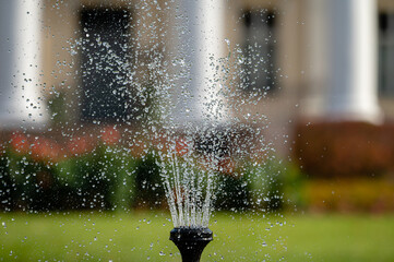 fountain splash close-up on a defocused background of an old manor, selective focus