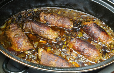 Closeup of isolated black metal casserole pot in oven with typical german fresh homemade beef roulades in sauce