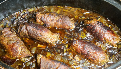 Closeup of isolated black metal casserole pot in oven with typical german fresh homemade beef roulades in sauce