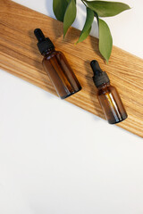 Natural essential oil or serum in brown glass bottle on a wooden podium. Alternative medicine, beauty skin care product. Copy space. Neutral background