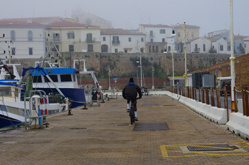 Obraz premium A bicycle enthusiast plays sports in the fog and moored boats