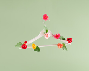 Clothes hanger floral arranged against pastel green background.  Minimal fashion concept....