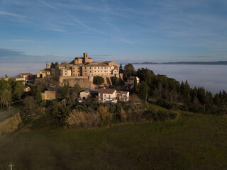Fototapeta na wymiar aerial view of the medieval village of Piticchio di Arcevia in the province of Ancona in the Marche region of Italy immersed in the fog