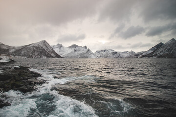 View from the isolated village of Husoy on the island of Senja, Norway. A very lonely fishing village. A view of the stormy Norwegian sea and snow-capped hills beyond the North Pole