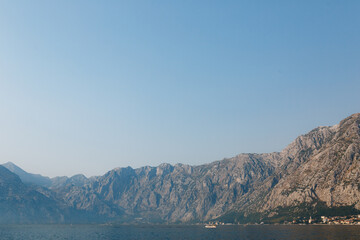 Kotor Bay surrounded by mountains in a light haze against a blue sky
