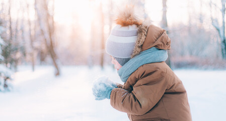 A boy blows snow off his hands winter lifestyle . Winter painting. Snow Park. Cold.