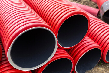 Gros plan sur plusieurs tubes gainés rouges pour réseaux électriques sur un chantier de construction