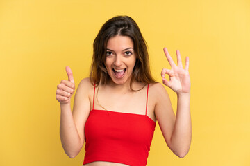 Young caucasian woman isolated on yellow background showing ok sign and thumb up gesture
