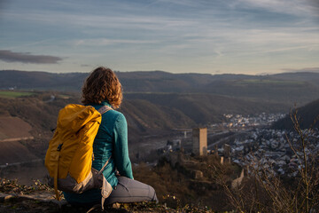 A hiker enjoys the view from above of the Niederburg and the Moselle valley