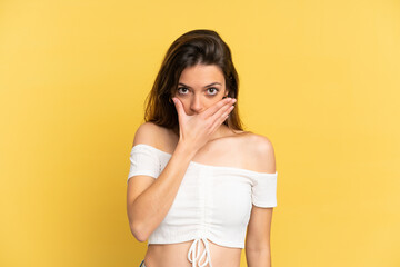 Young caucasian woman isolated on yellow background covering mouth with hand