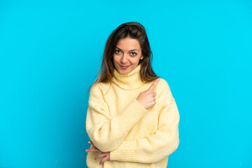 Fototapeta premium Young caucasian woman isolated on blue background pointing to the side to present a product