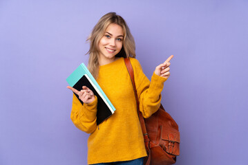 Teenager Russian student girl isolated on purple background pointing finger to the laterals and happy