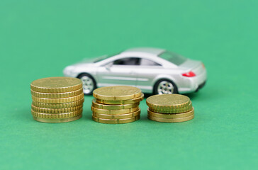 On a green background, coins with a toy car standing out of focus.