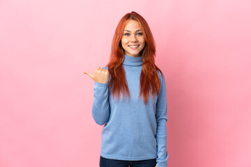 Teenager Russian girl isolated on pink background pointing to the side to present a product