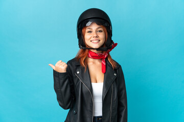 Teenager biker girl isolated on blue background pointing to the side to present a product