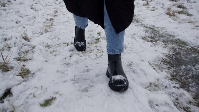 Feet of a woman walking in snow wearing winter shoes. Front view.