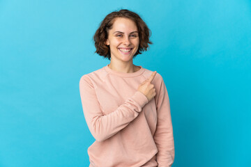 Young English woman isolated on blue background pointing to the side to present a product