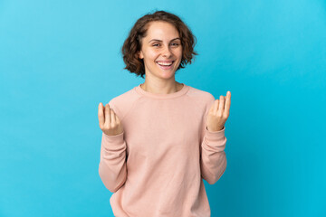 Young English woman isolated on blue background making money gesture