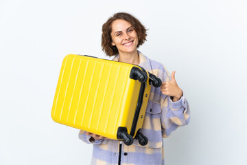 Young English woman isolated on white background in vacation with travel suitcase and with thumb up