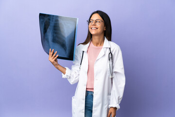 Young doctor woman holding a radiography thinking an idea while looking up