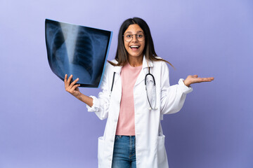 Young doctor woman holding a radiography with shocked facial expression