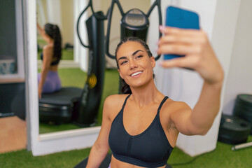 Young woman training while taking selfie with her smartphone in a gym