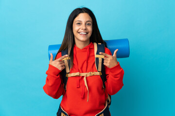 Young mountaineer woman with backpack giving a thumbs up gesture