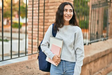 Young middle east student girl smiling happy holding book at the city.