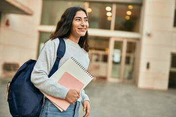 Young middle east student girl smiling happy holding book at the city.