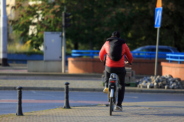 Mężczyzna na rowerze z plecakiem jedzie ścieżką rowerową w mieście, Wrocław.	