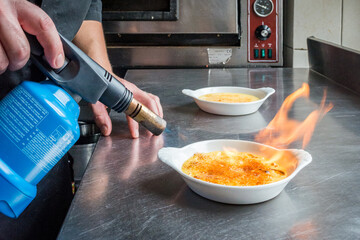 préparation d'une crème brûlée avec flamme, cuisine de  restaurant