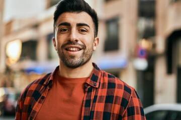 Young hispanic man smiling happy standing at the city.