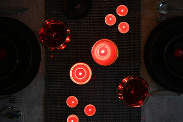 Top view of a romantic candlelight dinner and red wine in the dark.