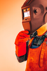 Fototapeta premium Heavy industry worker in protective suit with mask to protect eyes and face, vertical photo, close-up, fiery colors