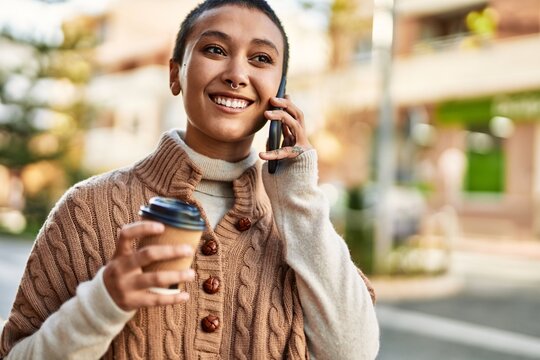 Young hispanic woman with short hair smiling happy drinking a cup of coffee and talking on the phone