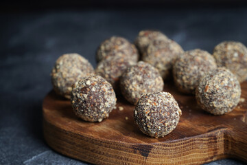 Healthy homemade energy balls on wooden plate. Vegan candies, sweets made of nuts and dates.