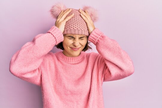 Young brunette woman wearing cute wool cap suffering from headache desperate and stressed because pain and migraine. hands on head.