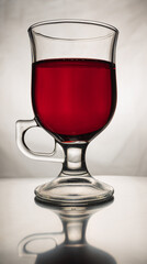 Still life with glass latte cup full of cherry juice and it's reflection