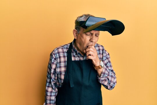 Handsome senior man with grey hair wearing welding protection mask feeling unwell and coughing as symptom for cold or bronchitis. health care concept.