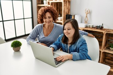 Mature mother and down syndrome daughter using computer laptop at home