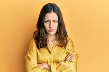 Young brunette woman wearing casual yellow shirt skeptic and nervous, disapproving expression on face with crossed arms. negative person.