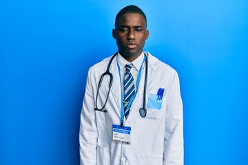 Young african american man wearing doctor uniform relaxed with serious expression on face. simple and natural looking at the camera.