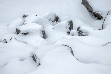 Grey boulders partially buried in deep snow