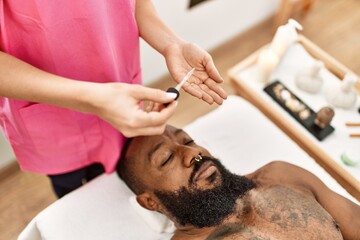 Young african american man having skin facial treatment at beauty center