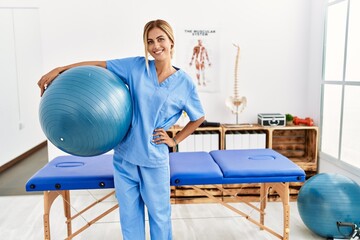 Young caucasian physio therapist smiling happy standing at the clinic