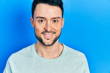 Fototapeta premium Young hispanic man wearing casual clothes looking positive and happy standing and smiling with a confident smile showing teeth
