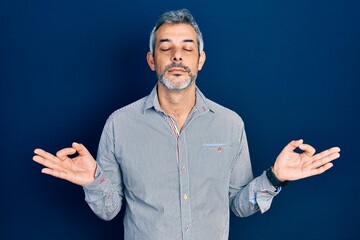 Handsome middle age man with grey hair wearing business shirt relax and smiling with eyes closed doing meditation gesture with fingers. yoga concept.