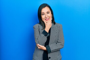 Middle age hispanic woman wearing business clothes looking confident at the camera smiling with crossed arms and hand raised on chin. thinking positive.