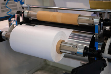 Moving roller with flat transparent polyethylene film at exhibition, trade show - part of automatic plastic bag making machine. Manufacturing, industry and technology equipment concept