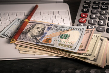 Various dollar money banknotes with stylish pen, calculator and portable computer